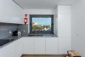 kuchnia z białymi szafkami i oknem w obiekcie Romantic Pool House w mieście Vila do Conde