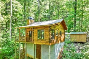 une cabane en rondins dans les bois avec une terrasse dans l'établissement Open Studio Lodge at Little Rock Creek, à Cherry Log