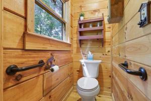a bathroom with a toilet in a wooden cabin at Open Studio Lodge at Little Rock Creek in Cherry Log