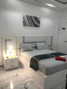 a white bedroom with a bed and a night stand at STUDIO MEUBLE DAKAR Suite 1 in Dakar