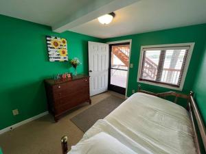 1 dormitorio con paredes verdes, 1 cama y ventana en Lakin' It Easy, en Middlebury
