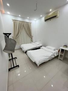 Zimmer mit 2 Betten, einem Schreibtisch und einem Stuhl in der Unterkunft شقة مميزه في القنفذة in Al Qunfudhah