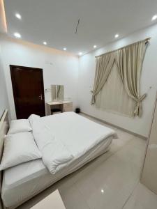 biała sypialnia z dużym łóżkiem i oknem w obiekcie شقة مميزه في القنفذة w mieście Al Qunfudhah