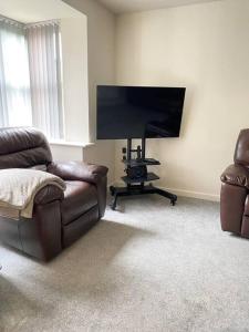 ein Wohnzimmer mit einem Sofa und einem Flachbild-TV in der Unterkunft 4-room detached furnished home with parking in Leicester