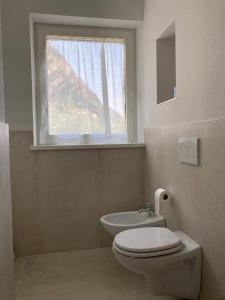 ein Bad mit einem WC, einem Waschbecken und einem Fenster in der Unterkunft La Casa sul Lago Apartments - Blue Wave Apartment in Limone sul Garda