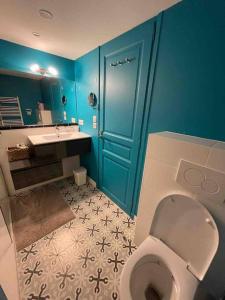 La salle de bains est pourvue de toilettes et d'un mur bleu. dans l'établissement Villa Bellevue, à Marcy-lʼÉtoile