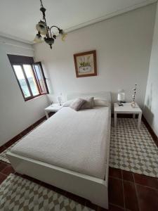 1 dormitorio con 1 cama blanca grande y 2 mesas en Casa El Mirador, en Suances