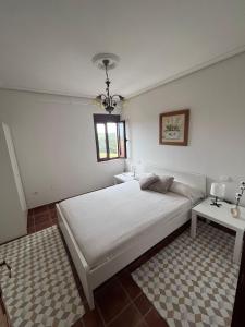 Un dormitorio con una gran cama blanca y una mesa en Casa El Mirador, en Suances