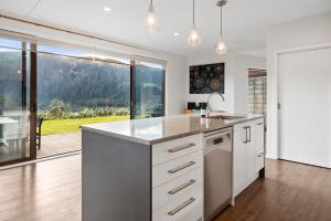 uma cozinha com armários brancos e uma grande janela em Lakehouse Retreat - Whakamaru Holiday Home em Mangakino
