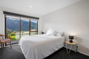 um quarto branco com uma cama e uma grande janela em Lakehouse Retreat - Whakamaru Holiday Home em Mangakino