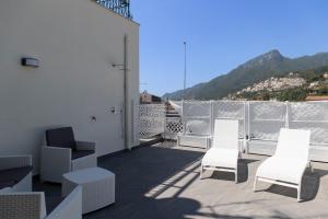 a balcony with white chairs and a view of a mountain at Al Chiaro di Luna Luxury Suites AMALFI COAST in Vietri
