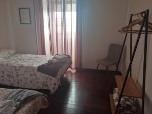 a room with two beds and a chair and a window at Casa dos biscoitos in Madalena
