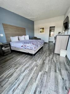 1 dormitorio con 1 cama y suelo de madera en Delux Inn Cleburne, en Cleburne