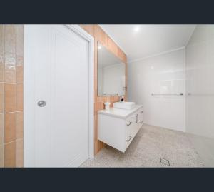 a white bathroom with a sink and a mirror at Brand New Luxury Abode on Shaw in Wagga Wagga