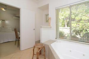 ein Bad mit einer Badewanne, einem Fenster und einem Bett in der Unterkunft Howie's Place Noosa in Noosaville