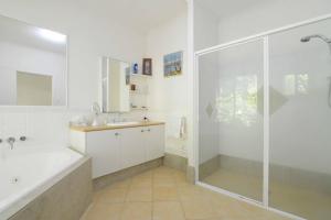 Howie's Place Noosa في نوسافيل: حمام مع دش وحوض استحمام ومغسلة