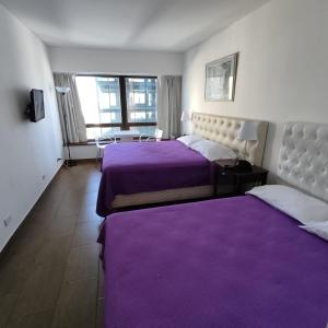 two beds in a hotel room with purple sheets at Corrientes y Esmeralda in Buenos Aires