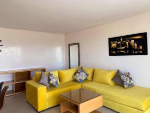 a living room with a yellow couch and a table at Appartement Les bienvenus in Essaouira