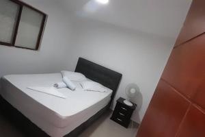 um quarto com uma cama com lençóis brancos e um espelho em Casa hotel Armenia em Armênia