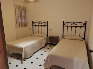 2 camas en un dormitorio con suelo blanco y negro en Casa RISAN, en Cañete la Real