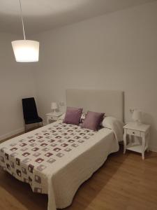 Un dormitorio blanco con una cama grande con almohadas moradas en VUT La Villa, en Vilagarcía de Arousa