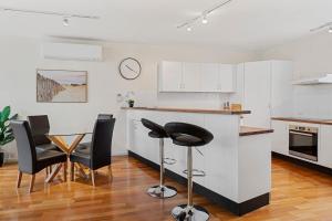 une cuisine avec des armoires blanches et une table et des chaises dans l'établissement Centre Stage - Stroll to the Waterfront, à Hobart