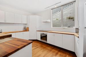une cuisine avec des armoires blanches et une fenêtre dans l'établissement Centre Stage - Stroll to the Waterfront, à Hobart 8 autres photos