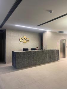 Un hombre sentado en un mostrador de recepción en un vestíbulo. en One Manquehue Aparthotel, en Santiago