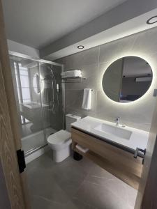 Un baño con lavabo, inodoro y espejo. en One Manquehue Aparthotel, en Santiago