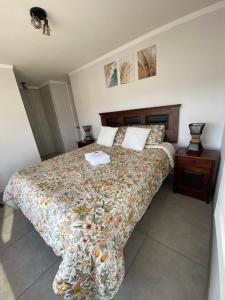 ein Schlafzimmer mit einem Bett mit geblümter Tagesdecke in der Unterkunft Hermoso y amplio Departamento frente al mar in Coquimbo + 22 Fotos