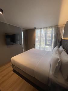 Un dormitorio con una gran cama blanca con ventana. en One Manquehue Aparthotel, en Santiago