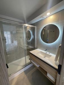 uma casa de banho com um chuveiro, um lavatório e um espelho. em One Manquehue Aparthotel em Santiago
