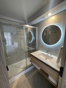 Un baño con ducha, lavabo y espejo. en One Manquehue Aparthotel, en Santiago