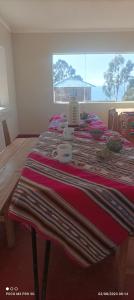 una habitación con una mesa con una manta roja. en Rufino y Lucrecia MUNAY TIKA WASI Posada Oha en Puno