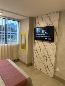 1 dormitorio con TV en la pared y 1 cama en Lindo Apt de 1 quarto no Sudoeste 103, próximo do centro de convenções Ulysses Guimarães, mane garrincha e ministérios, en Brasilia