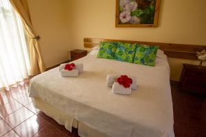 a bedroom with a white bed with red flowers on it at Hostal Uruhao in Hanga Roa +64 photos