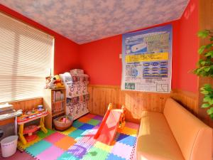 una camera per bambini con pareti rosse e un'area giochi di 北方温泉四季の里　七彩の湯 a Takeo