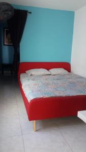 Una cama roja en una habitación con una pared azul en Casa Amplia Completa Privada para Familias en Santa Marta