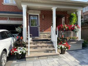 a house with a blue door and stairs with flowers at Basement apartment in Richmond Hill