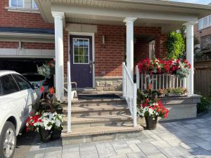 een huis met een blauwe deur en een trap met bloemen bij Basement apartment in Richmond Hill