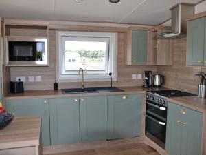 een keuken met blauwe kasten, een wastafel en een raam bij Brand new chalet on a completely new luxury resort 