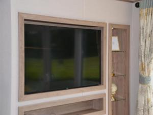een flatscreen-tv in een kamer met een raam bij Brand new chalet on a completely new luxury resort 