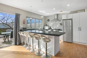 a kitchen with a large island with bar stools at Family Harmony - Waihi Beach Holiday Home in Waihi Beach