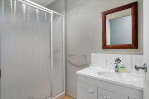 a white bathroom with a shower and a sink at Family Harmony - Waihi Beach Holiday Home in Waihi Beach +18 photos