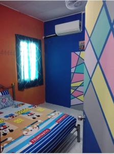 ein Schlafzimmer mit einem Bett mit einer farbenfrohen Wand in der Unterkunft Blue Homestay Teluk Kemang Port Dickson in Port Dickson