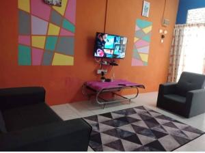 ein Wohnzimmer mit einem TV, einem Sofa und einem Tisch in der Unterkunft Blue Homestay Teluk Kemang Port Dickson in Port Dickson