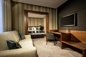 una camera d'albergo con divano, scrivania e letto di Best Western Premier Hotel Slon a Lubiana