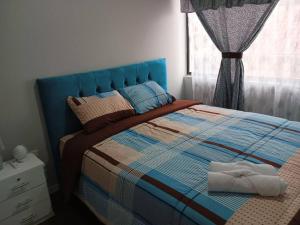 1 dormitorio con 1 cama con cabecero azul y ventana en Departamento Doble con Jacuzzi en Cuenca
