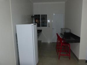 uma cozinha com um frigorífico branco e cadeiras vermelhas em Apto Mobiliado Ar Cond Residencial Rios em Barretos
