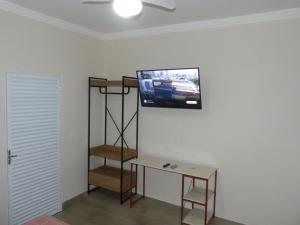 Cette chambre dispose d'une télévision sur un mur et d'une table. dans l'établissement Apto Mobiliado Ar Cond Residencial Rios, à Barretos